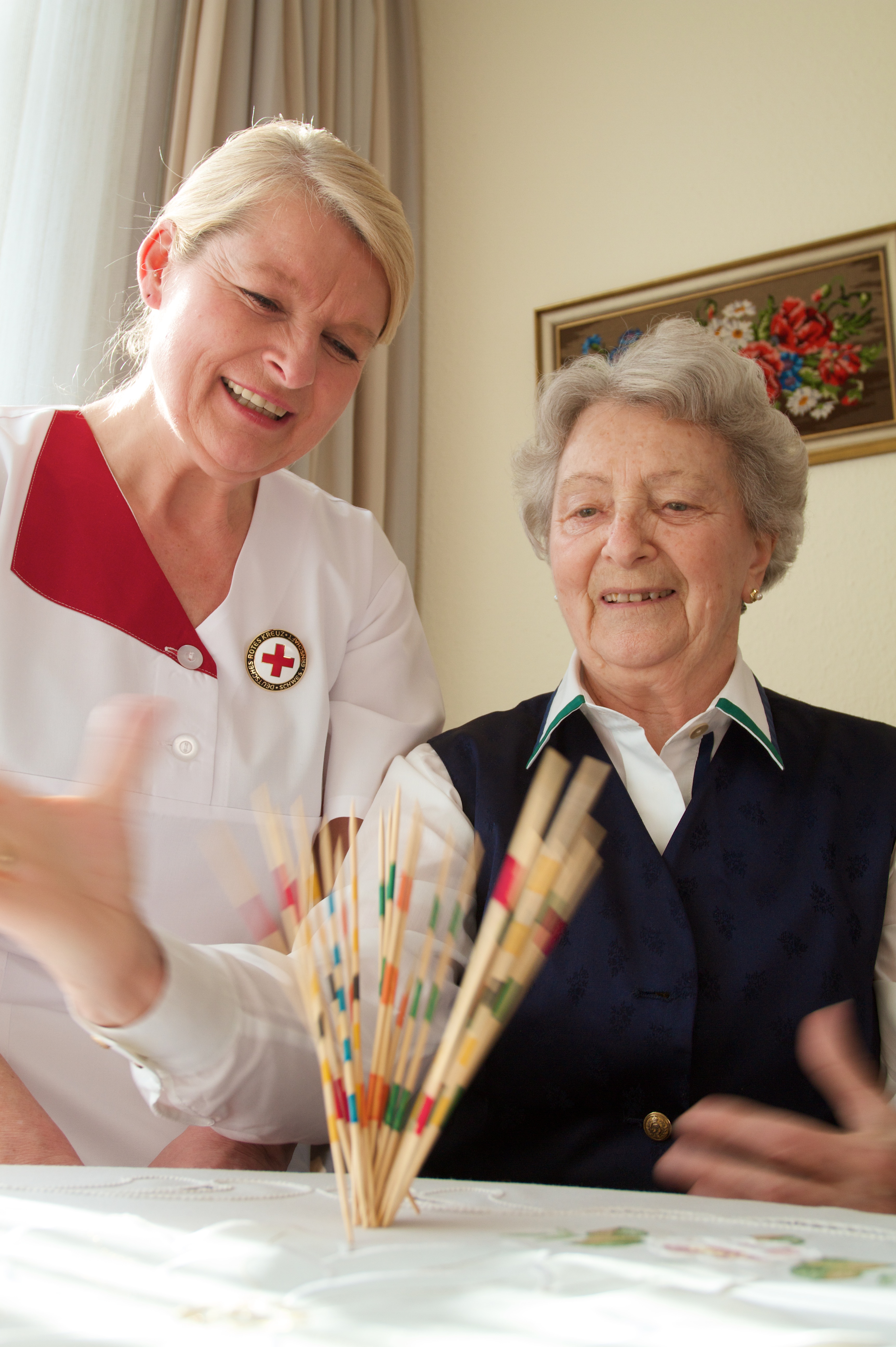 Seniorin spielt mit Altenpflegerin vom DRK Arnsburg Mikado, es wird die Motorik, Konzentration und soziale Interaktion gefördert.