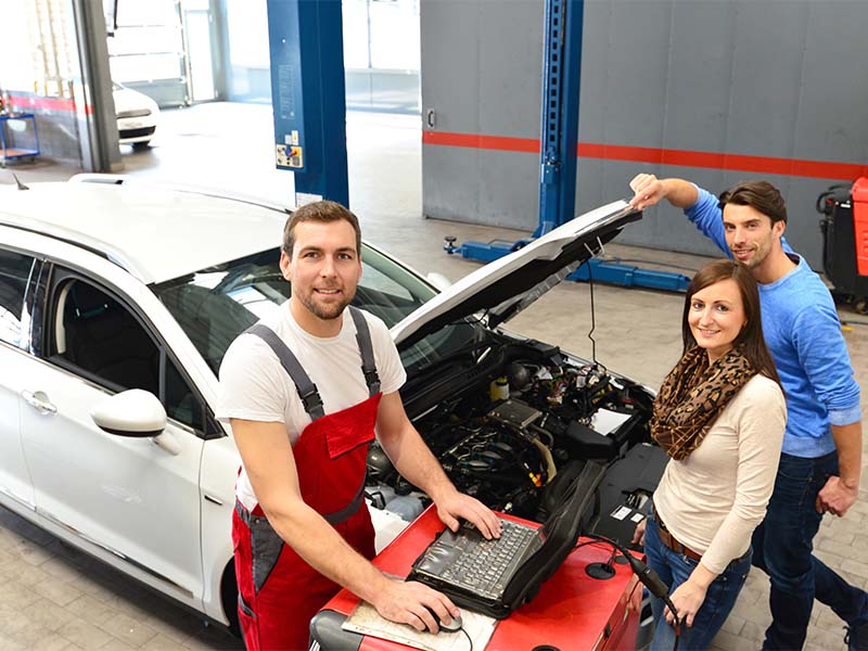 Ein Automechaniker prüft das Auto eines Kunden und Kundin in der Werkstatt bei der Autoinspektion in Meinerzhagen