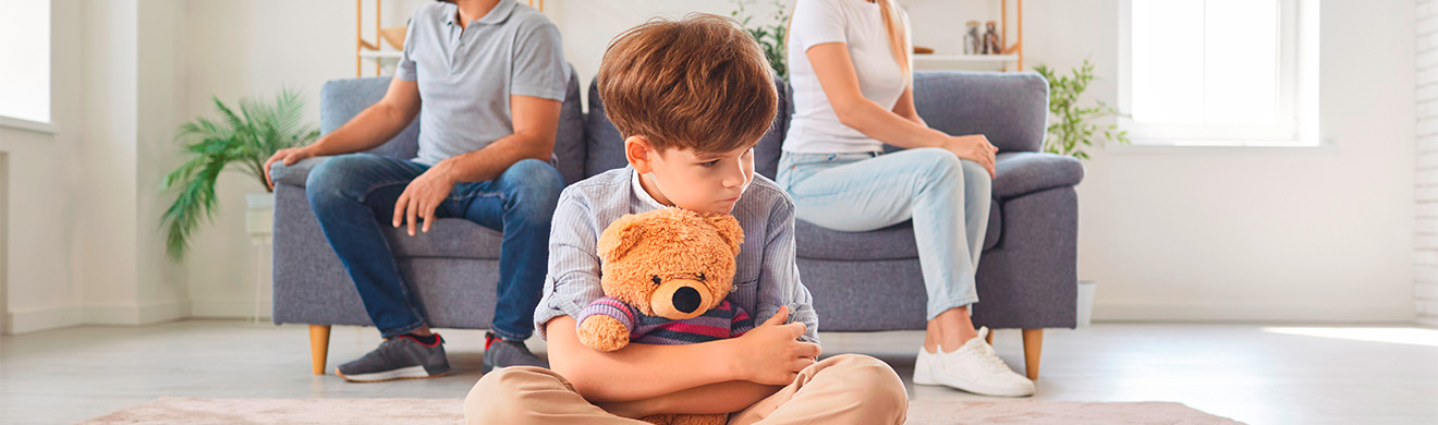 Trauriges Kind mit Teddybär sitzt zwischen Eltern nach Streit – Symbolbild für Familienrecht in Meschede.