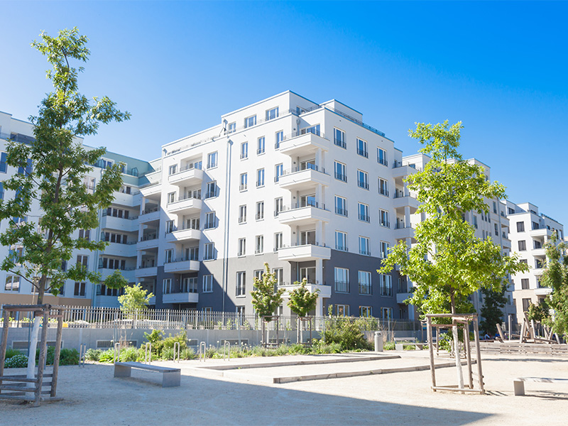 Wohnhausanlage mit modernen Gebäuden und parkähnlicher Grünfläche in Deutschland, geeignet für Hausverwaltung und Immobilienmanagement.