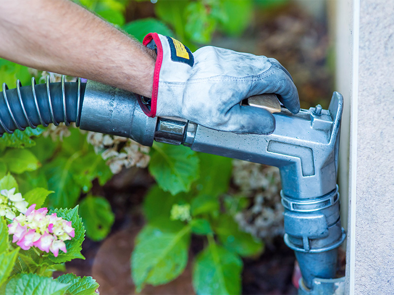 Mitarbeiter füllt Heizöltank an einem Haus durch Zapfhahn, pünktliche Versorgung beim Heizöl liefern im Winter.