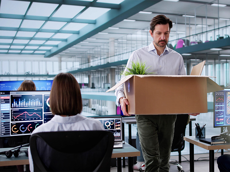 Mitarbeiter packt persönliche Dinge in Karton nach fristloser Kündigung in Menden, zeigt emotionale Reaktion auf Entlassung.