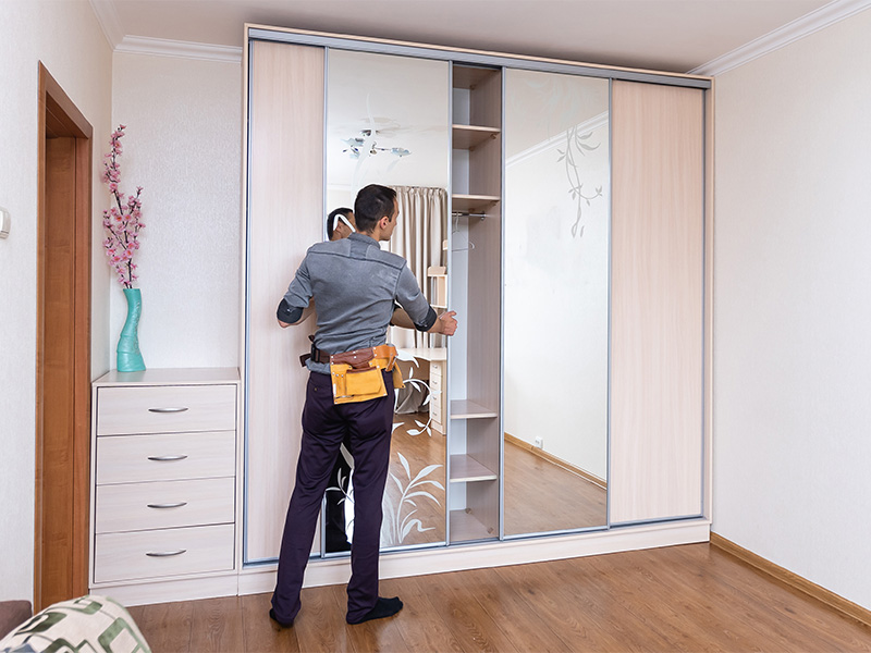 Handwerker montiert einen Einbauschrank aus Holz im Schlafzimmer – fein säuberlich installiert.