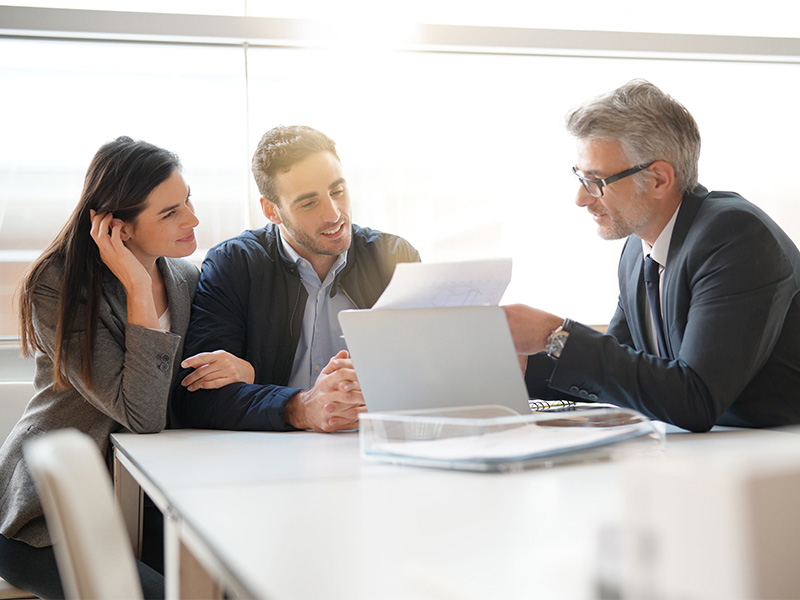 Junges Paar im Beratungsgespräch mit Finanzexperten, der ihnen verständlich Schritte zum erfolgreichen Vermögensaufbau in Arnsberg erklärt.