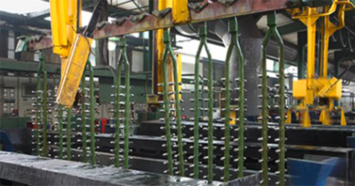 Metallteile auf Gestellen vorbereitet für Oberflächenveredelung, ideal für größere Bauteile und präzise Beschichtung.