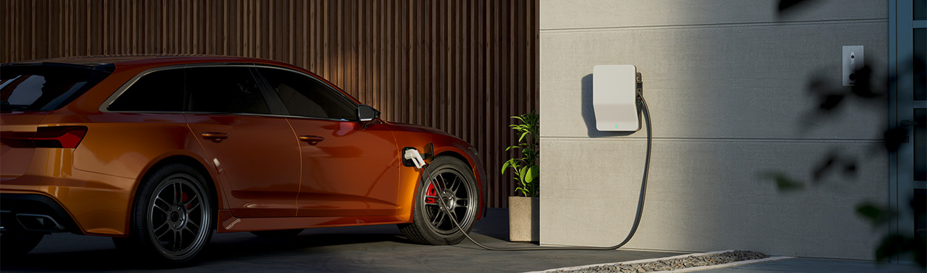 Ein Elektroauto wird an einer modernen Wallbox auf einem Wohngebäude in Meinerzhagen aufgeladen.